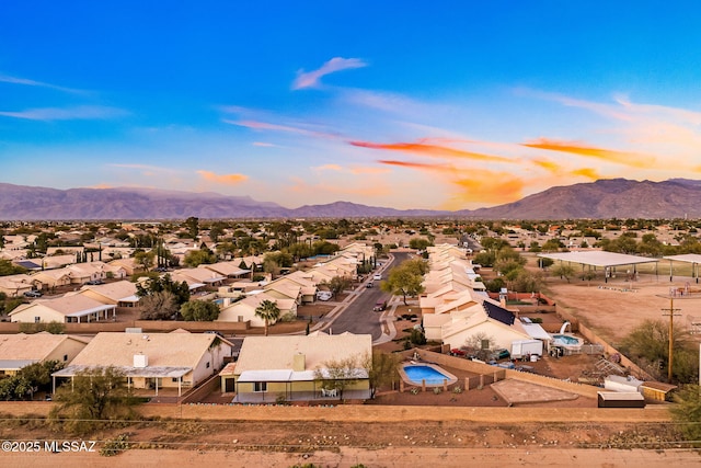 aerial view at dusk featuring a mountain view and a residential view