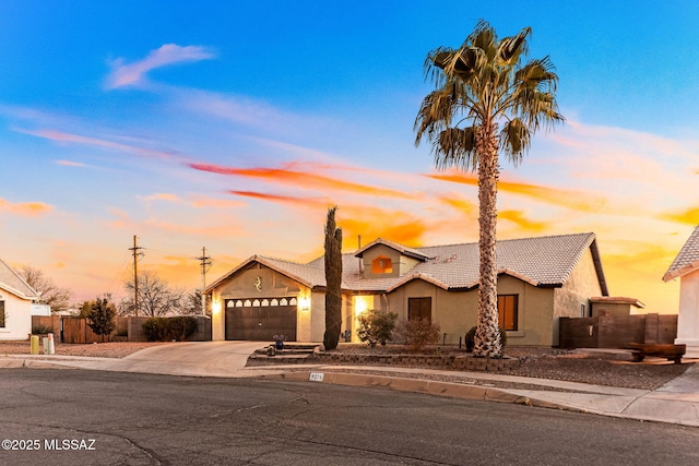 view of front of property featuring fence, a tiled roof, concrete driveway, stucco siding, and an attached garage