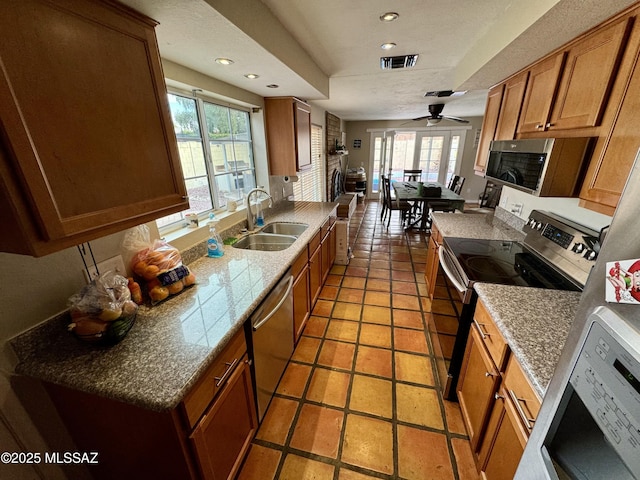 kitchen with appliances with stainless steel finishes, brown cabinetry, visible vents, and a sink