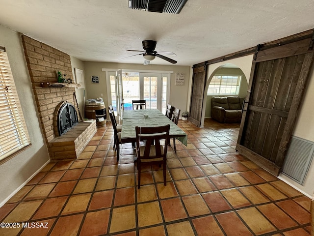 dining room featuring a barn door, visible vents, a textured ceiling, and tile patterned floors