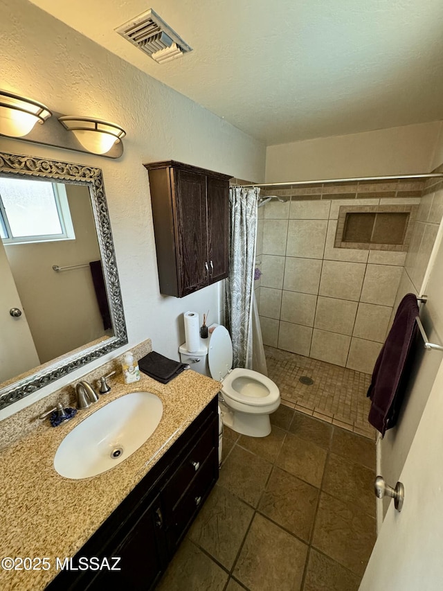 full bathroom with visible vents, a textured wall, toilet, a tile shower, and vanity