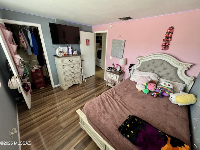 bedroom featuring a closet, washer / dryer, wood finished floors, and visible vents