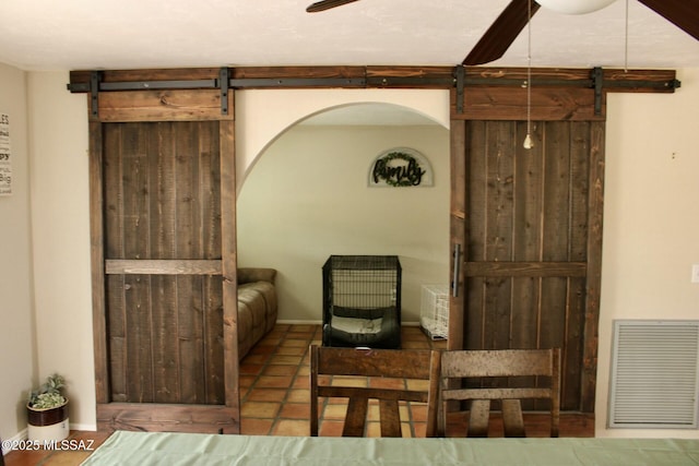 living area featuring ceiling fan, a barn door, and visible vents