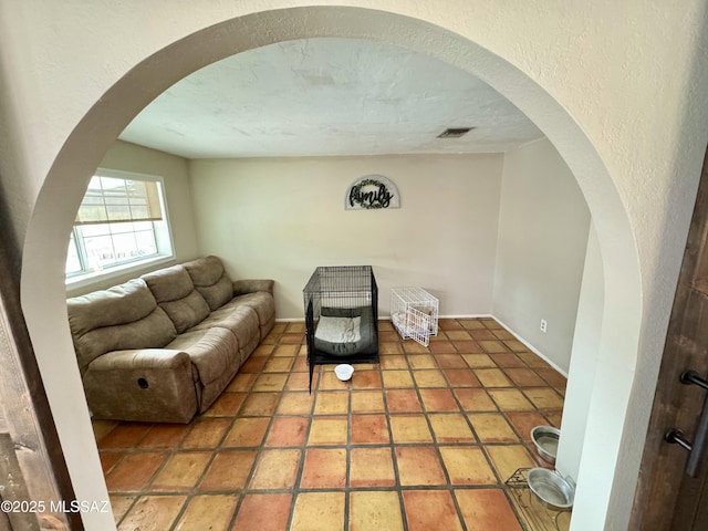 living room with arched walkways, visible vents, a textured wall, a textured ceiling, and tile patterned floors