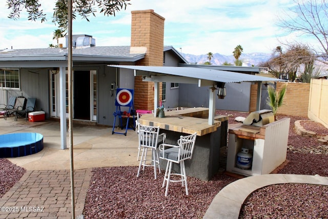 view of patio featuring fence, outdoor dry bar, and a mountain view