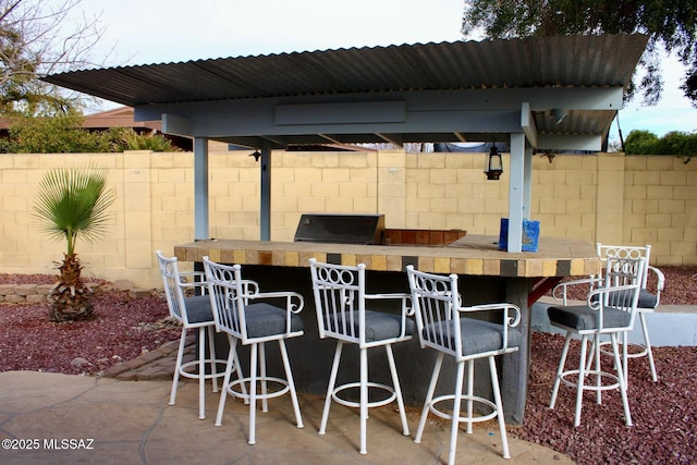 view of patio featuring a bar, fence, and area for grilling