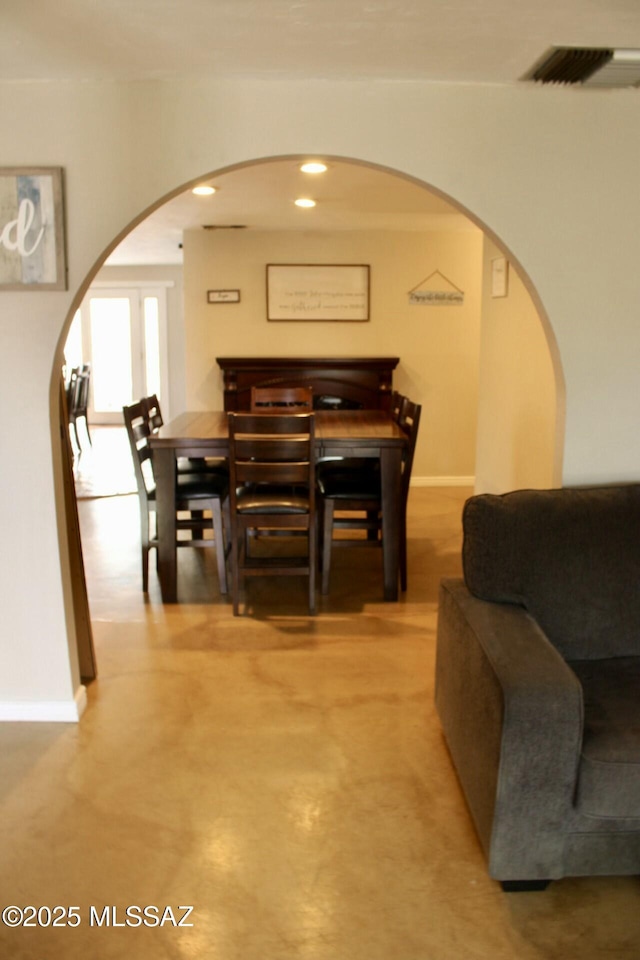 dining area with arched walkways, visible vents, baseboards, and recessed lighting