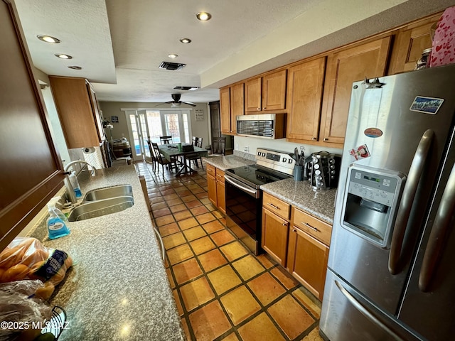 kitchen featuring visible vents, brown cabinets, stainless steel appliances, light countertops, and a sink