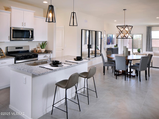 kitchen featuring a sink, stainless steel appliances, an island with sink, and decorative light fixtures