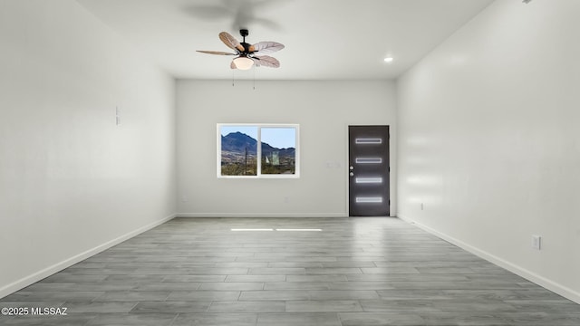 unfurnished room with a ceiling fan, baseboards, and wood finished floors