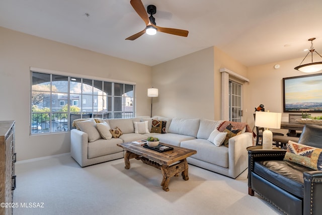 living room with light carpet, a ceiling fan, and baseboards