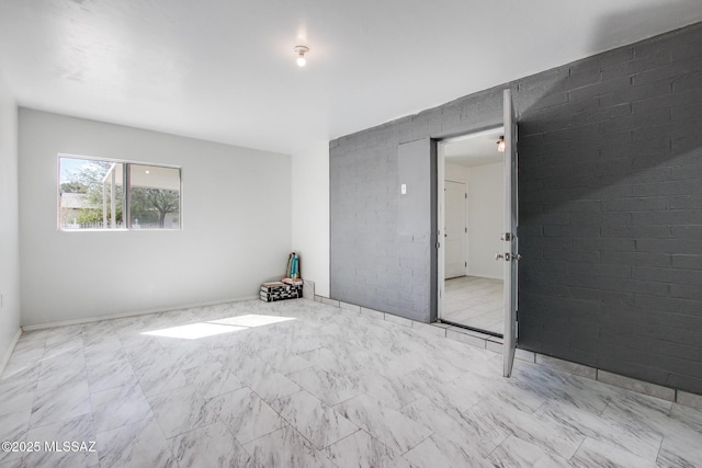 spare room with marble finish floor and brick wall