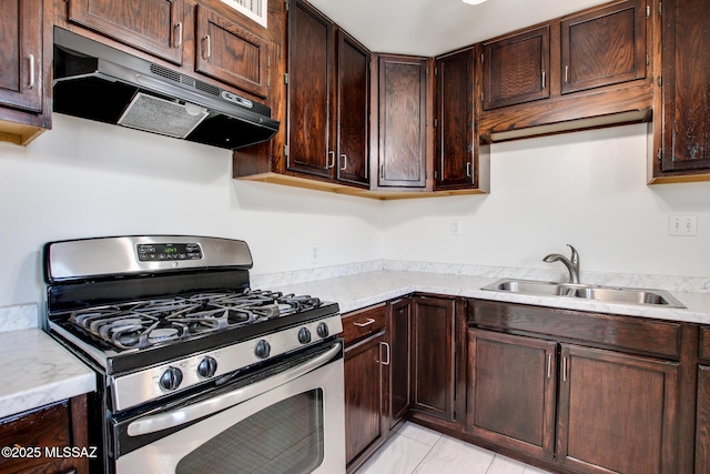 kitchen with dark brown cabinets, stainless steel gas range oven, a sink, and under cabinet range hood