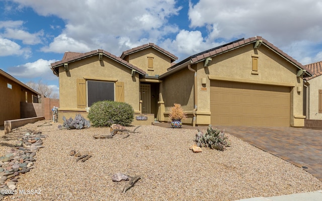 view of front facade with decorative driveway, a tile roof, an attached garage, and stucco siding