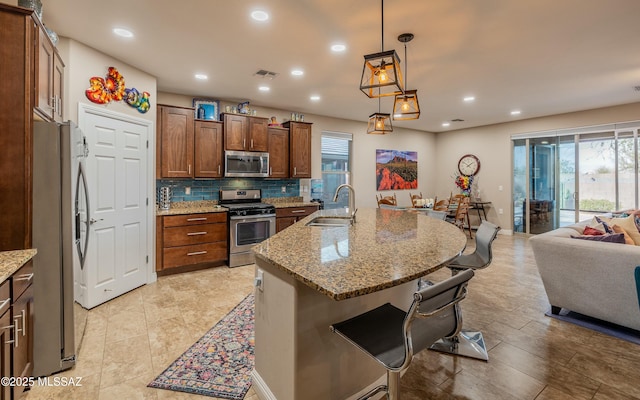 kitchen featuring a breakfast bar, open floor plan, a sink, stainless steel appliances, and backsplash