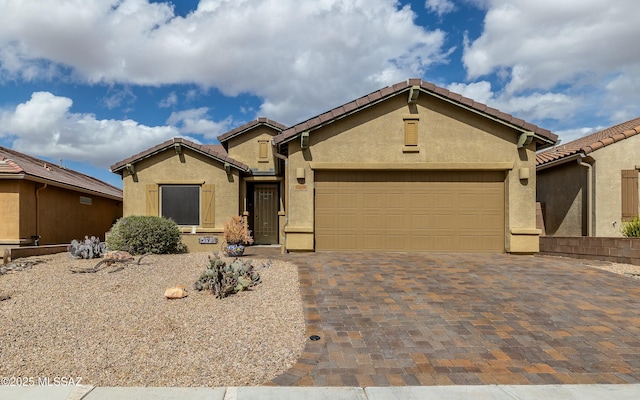 view of front of property with an attached garage, a tile roof, decorative driveway, and stucco siding