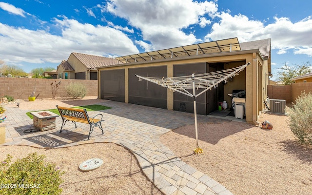 exterior space with a fire pit, a tiled roof, cooling unit, a patio area, and stucco siding