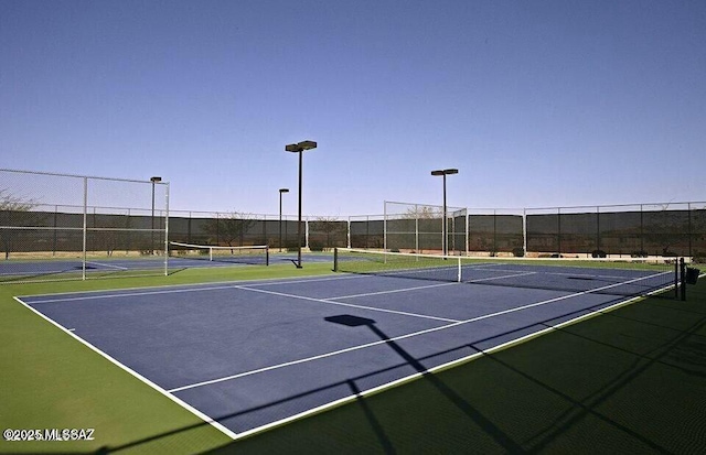 view of tennis court with community basketball court and fence