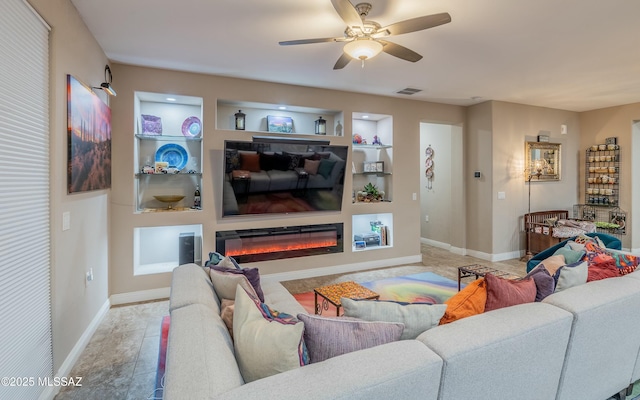 living room with built in shelves, visible vents, a ceiling fan, a glass covered fireplace, and baseboards