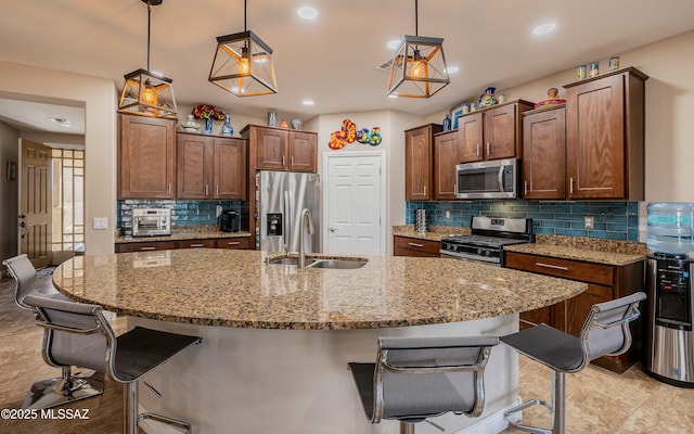 kitchen featuring appliances with stainless steel finishes, a sink, a kitchen breakfast bar, and light stone countertops