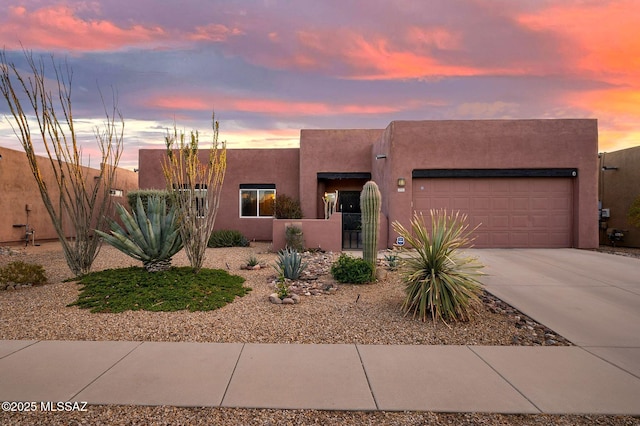 southwest-style home with stucco siding, a gate, a fenced front yard, concrete driveway, and a garage