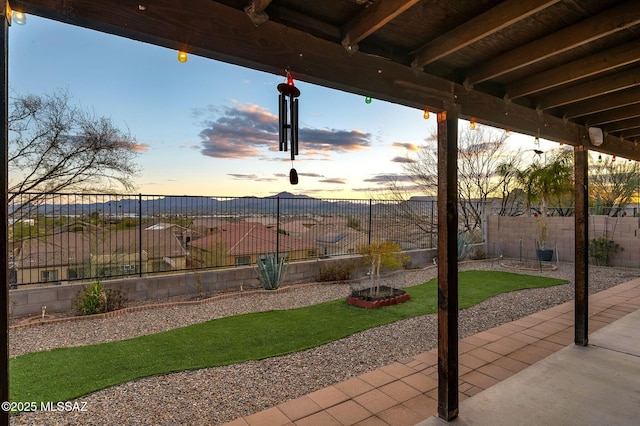 patio terrace at dusk featuring a fenced backyard