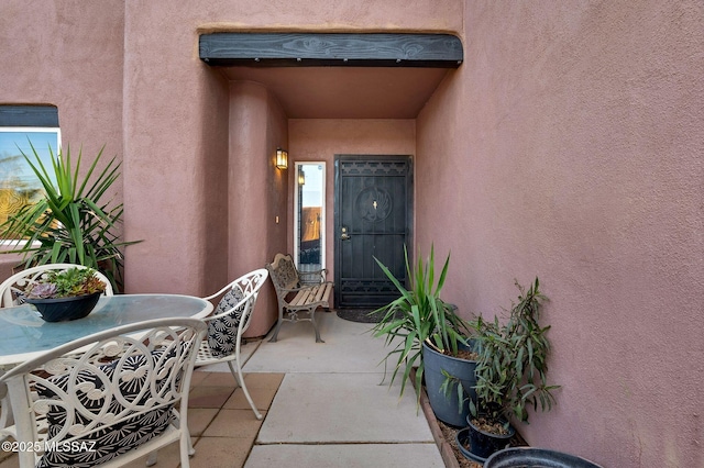 view of exterior entry featuring a patio area and stucco siding