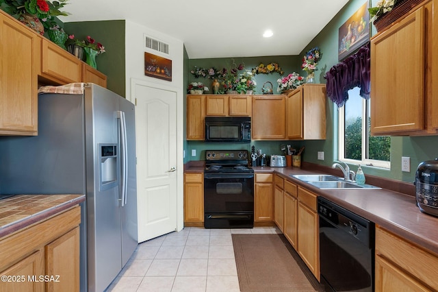 kitchen featuring light tile patterned floors, visible vents, black appliances, and a sink