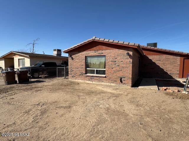 view of side of home with a tiled roof, fence, and brick siding