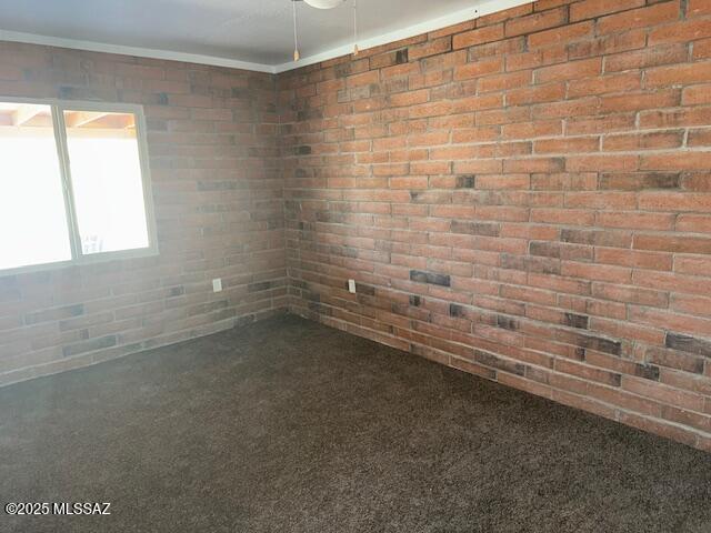 spare room featuring brick wall and ornamental molding