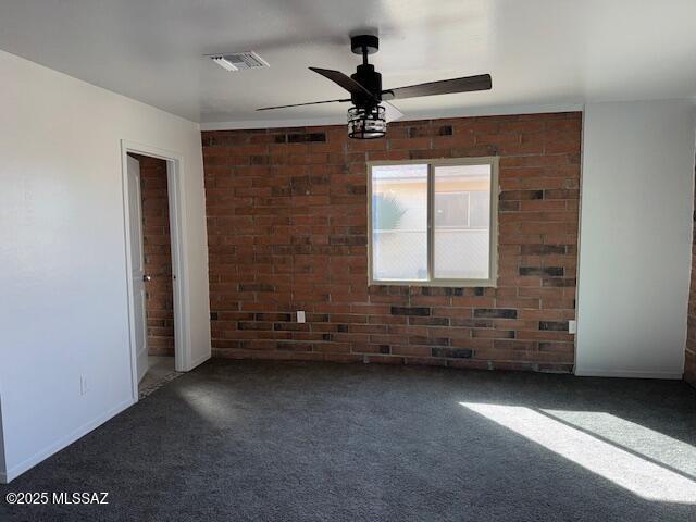 spare room featuring brick wall, visible vents, ceiling fan, and carpet flooring