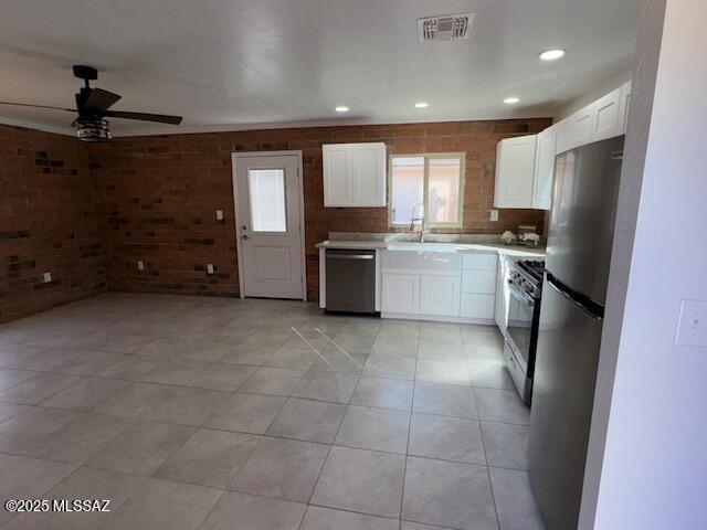 kitchen featuring stainless steel appliances, a sink, visible vents, white cabinets, and light countertops