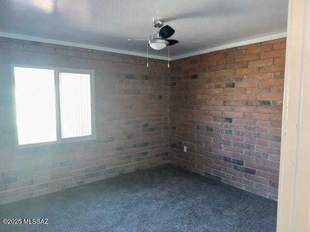 carpeted empty room featuring brick wall and a ceiling fan