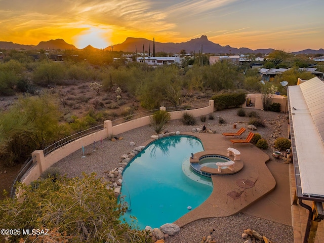 view of pool with a fenced backyard, a mountain view, and a pool with connected hot tub