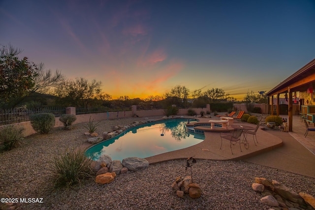 view of swimming pool featuring a patio, a fenced backyard, and a pool with connected hot tub