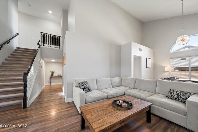 living room featuring visible vents, wood finished floors, stairway, a high ceiling, and baseboards