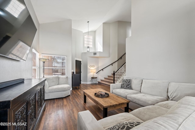 living area with stairs, visible vents, a high ceiling, and dark wood-style flooring