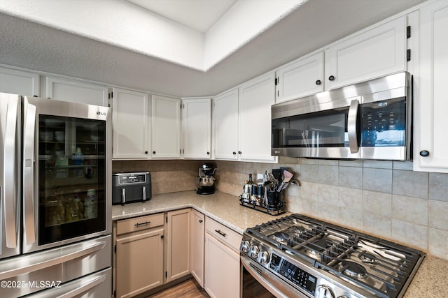 kitchen with decorative backsplash, white cabinets, and appliances with stainless steel finishes