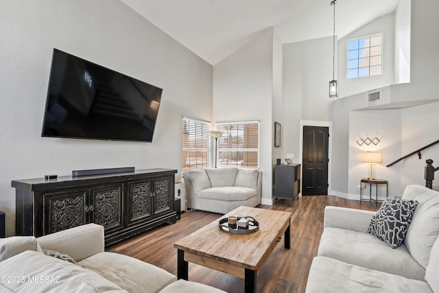 living area featuring visible vents, lofted ceiling, baseboards, and wood finished floors