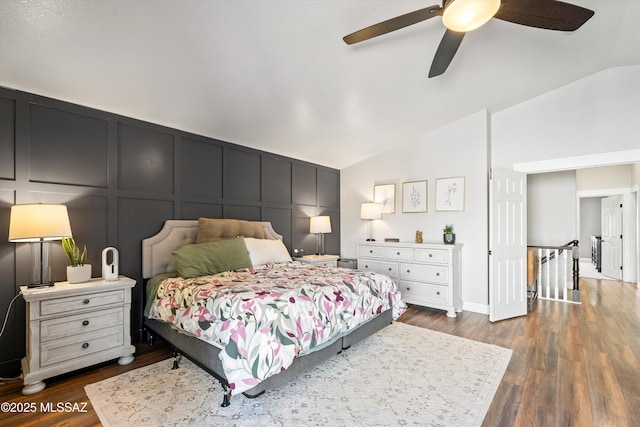 bedroom featuring lofted ceiling, a decorative wall, a ceiling fan, and dark wood-type flooring