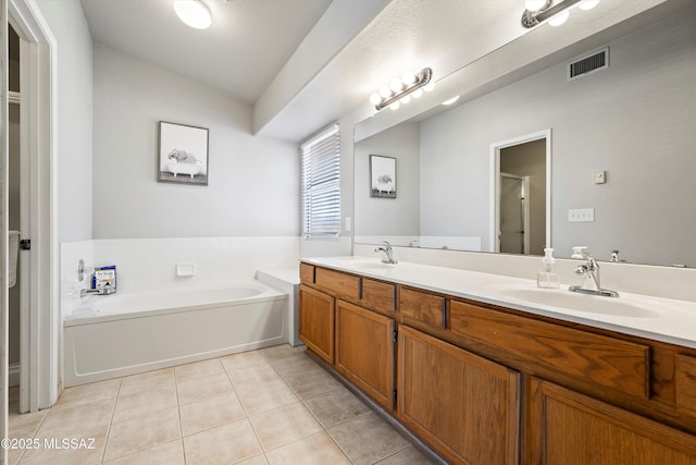 bathroom featuring tile patterned flooring, a bath, visible vents, and a sink