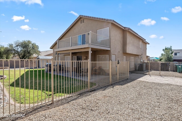 rear view of property featuring a yard, stucco siding, a patio, and a balcony