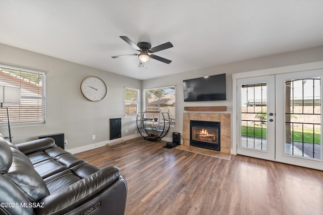 living room with a tile fireplace, wood finished floors, baseboards, and ceiling fan