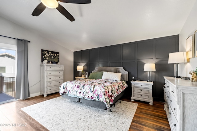 bedroom with ceiling fan, lofted ceiling, dark wood-style flooring, a decorative wall, and access to outside