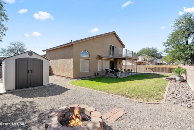 rear view of property with stucco siding, a patio, an outdoor fire pit, a storage shed, and an outdoor structure