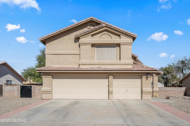 traditional-style home featuring stucco siding, fence, concrete driveway, and a gate