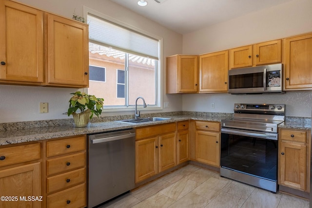 kitchen with light stone counters, stainless steel appliances, and a sink