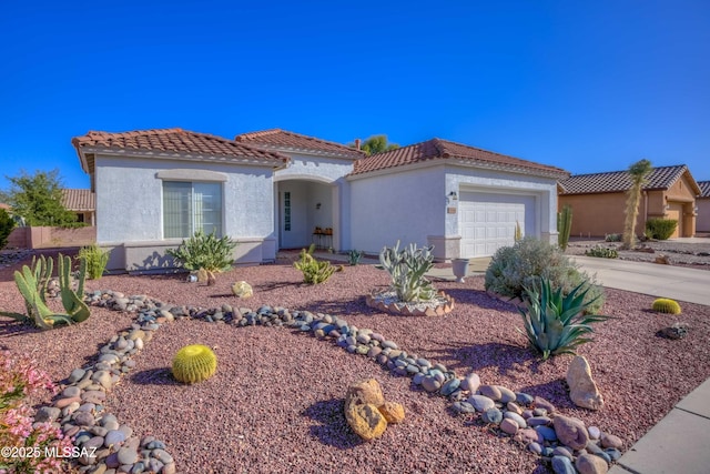 mediterranean / spanish house featuring an attached garage, driveway, a tile roof, and stucco siding