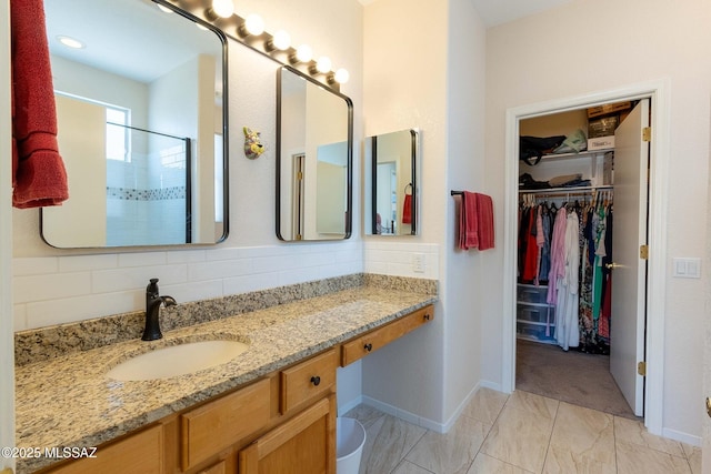 bathroom featuring baseboards, decorative backsplash, a shower, a spacious closet, and vanity