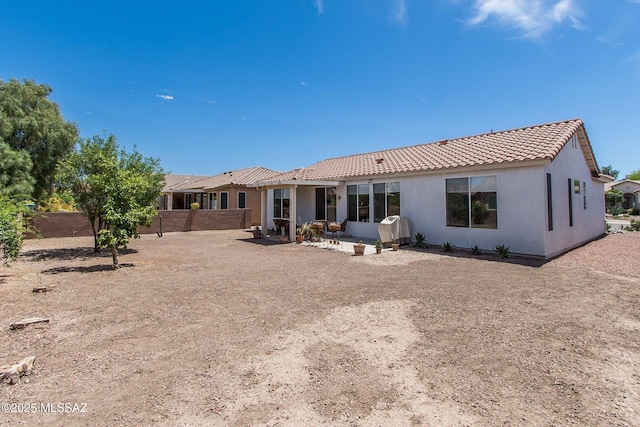 back of house featuring stucco siding, fence, a patio, and a tiled roof